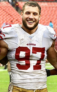 Nick Bosa in a 49ers jersey (with no helmet) smiling.