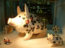 A large pig with comical features sits among other items in a shop display.