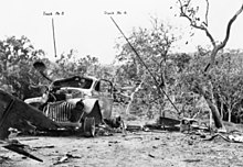 Destroyed vehicles amidst a devastated jungle scene