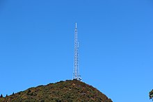A gray lattice tower on a forested mountain peak