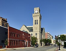 A gray brick Romanesque Revival building with a signature clock tower