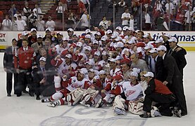 The Detroit Red Wings team, coaches, and support staff pose on the ice with the Stanley Cup.