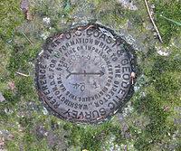 Bronze disc with inscribed arrow, set in concrete