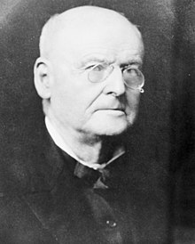 Black and white portrait photograph of an elderly man wearing glasses
