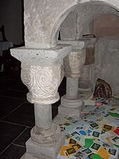 St Melangell's shrine is held up by carved stone columns, with a pile of colourful prayer cards lying underneath.