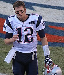 Brady clutching his fist and holding his helmet as he walks off the field