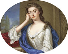 A portrait in a landscape oval format of a young lady with light-brown eyes and hair, wearing a white blouse or dress, sitting at a window giving on a garden with some trees