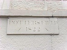 A white wall carries a stone plaque engraved with the word "Pottersfield" in upper case letters. Below this are the numerals "1822".