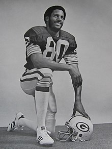 Lofton posing in his uniform on a football field