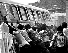 Rioters attempting to push over a bus