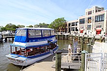 Modern color photo of a boat on a sunny day docked to a wharf with a large building behind it