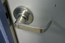 A silver-colored door handle on a white door