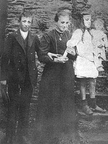 black and white photo of three siblings: a teenaged boy, a young woman, and a small girl.