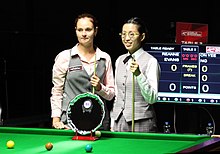 Two women standing at a snooker table