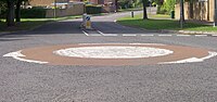 A mini-roundabout in the UK, where a painted white circle is used as centre. The arrows show the direction of traffic.