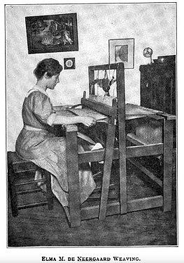 Elna M. de Neergaard, seated at a floor loom, weaving