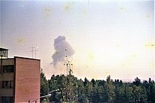 Photograph of the city and trees with an explosion on the horizon