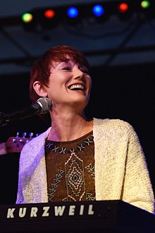 Lari White, singing into a microphone. Before her is a keyboard labeled "Kurzweil"