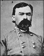 Black and white photo shows a dark-haired man with a large moustache. He wears a double-breasted gray uniform with general's stars on the collar.