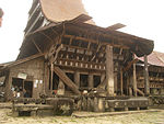 Photograph of a traditional wooden house with a high triangular roof.