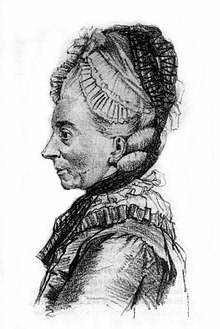 An old lady's face and upper body from profile. She had a big nose and start facial features. Her hair is braided under a cap with a black veil on top.