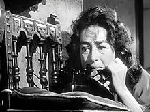 Facial shot of a dishevelled middle-aged woman on the telephone.
