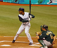 A baseball player in white and dark green