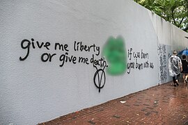 Pepe the Frog as a graffiti alongside the famous quote "Give me liberty or give me death" and a V for Vendetta symbol, October 2019