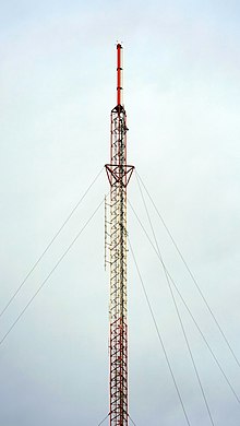 A red-and-white tower topped by a red cylindrical antenna