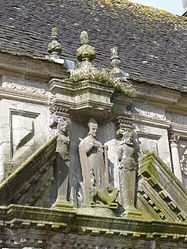 The sculpture over the ossuary entrance:Saint Pol Aurélien with the dragon he had captured and with two "termes gainé" on either side. A "termes gainé" is a sculptural device where the head is human but the body is in effect a carved pedestal.