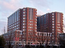 A red, four-story building with two eight-story towers rising above it