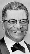 Black and white portrait of Lombardi wearing a tuxedo and smiling