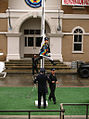 A police officer is hoisted up a flag pole.