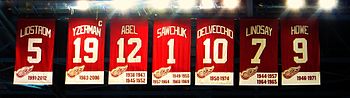 The banners for retired numbers that hang at Joe Louis Arena. The banners read, from left to right − LIDSTROM 5 − YZERMAN 19 − SAWCHUK 1 − DELVECCHIO 10 − LINDSAY 7 − ABEL 12 − HOWE 9