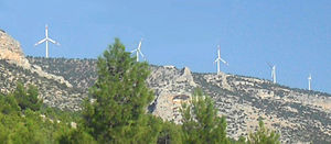 Five wind turbines atop a hill as seen from a distance