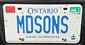 Personalized plate (front) attached to a pickup truck. As a pickup truck it should otherwise bear a black on white commercial plate, but the personalized plate is blue on white. Validation and "personal use" tags are affixed to the front plate, as in the case of other pickups.