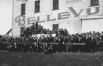 Black and white photo of a crowd looking at a field in front of a building that says Bellevue