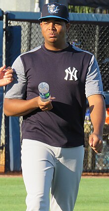 Rony García photographed in 2019, baseball player holding a bottle of water and walking towards the photographer