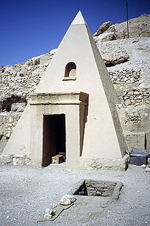 A small pyramid with a large doorway in a courtyard