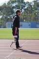 A Paralympic track athlete walks with a prosthetic leg designed for racing.