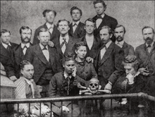 A black and white photograph of white male medical students posing with a human skull, with an African American woman (Sarah Loguen Fraser) sitting in the center front.