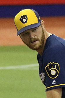 A man in a navy blue baseball uniform with yellow and white trim and a navy and yellow cap