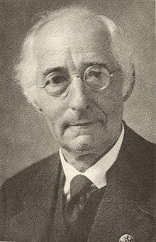 Old, clean-shaven man with white hair and round spectacles
