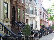 A view down a street with rowhouses in brown, white, and various shades of red