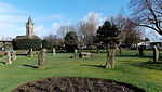 a stone circle in a park. In the background are trees, a bandstand and a church tower
