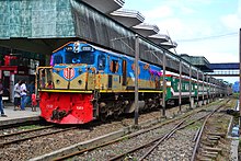 Green passenger train pulled by a blue diesel engine