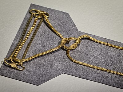 Gold two-pin fibula with chain tied in a Heracles knot
