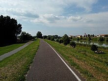 Photo shows a paved footpath and a river.