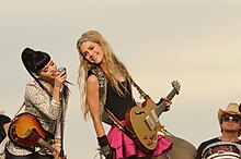 Two young woman performing while holding guitars