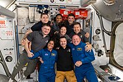 The seven Expedition 71 crew members gather with the two Crew Flight Test members for a team portrait aboard the space station